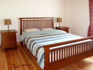ein Schlafzimmer mit einem Bett mit zwei Nachttischen und zwei Lampen in der Unterkunft 1 Clancy Cottages in Kilkieran