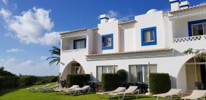 a white building with chairs and tables in front of it at Pestana Palm Gardens in Carvoeiro