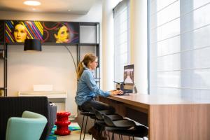 a woman sitting at a desk with a laptop at Aparthotel Adagio Köln City in Cologne