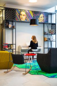 a woman sitting at a desk in an office with a laptop at Aparthotel Adagio Köln City in Cologne