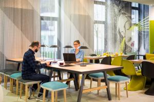 two people sitting at a table with laptops at Aparthotel Adagio Köln City in Cologne