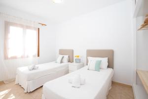 2 camas en una habitación con paredes blancas en Villa Margarita, en Es Mercadal