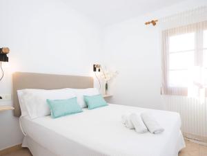 Una cama blanca con dos almohadas azules. en Villa Margarita, en Es Mercadal
