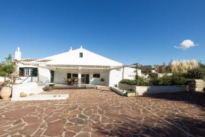 a white house with a large stone patio at Finca Calafi Nou in Ferreries