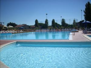 a large swimming pool in a resort with chairs at Villaggio Mare Si in Follonica