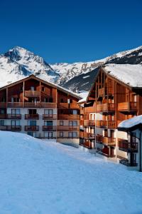 a hotel in the snow with mountains in the background at Lagrange Vacances Les Valmonts de Val Cenis in Lanslebourg-Mont-Cenis