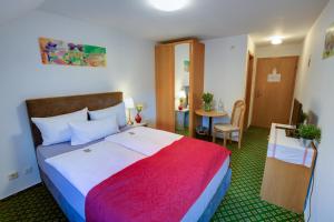 ein Hotelzimmer mit einem großen Bett und einem Tisch in der Unterkunft Hotel Leo Mühlhausen in Mühlhausen