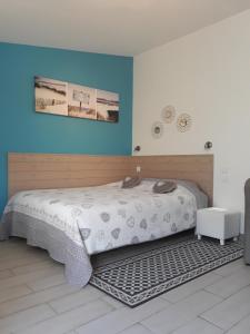 ein Schlafzimmer mit einem großen Bett und einer blauen Wand in der Unterkunft Chevrefeuille et Eglantine in LʼÎle-dʼOlonne