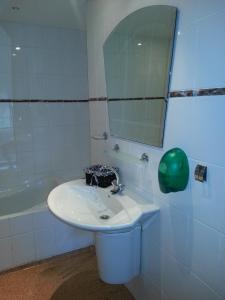 ein Badezimmer mit einem Waschbecken, einem Spiegel und einer Badewanne in der Unterkunft Café Brasserie Het Heerenhuis in Het Kalf