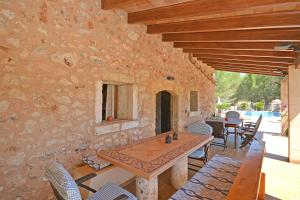 um pátio com uma mesa e cadeiras e uma parede de pedra em Villa Alba em Llubí