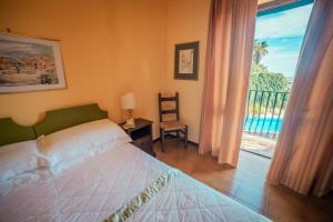 a bedroom with a bed and a large window at Hotel Villa Sirina in Taormina