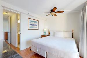 a bedroom with a white bed and a ceiling fan at Island Colony Suites in Honolulu