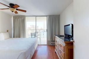 een slaapkamer met een bed en een flatscreen-tv bij Island Colony Suites in Honolulu