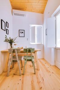 uma sala de jantar com uma mesa de madeira e 2 cadeiras verdes em A Casa D'Amelie em Faro