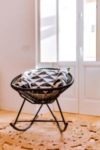 a black basket chair sitting on a rug in a room at A Casa D'Amelie in Faro