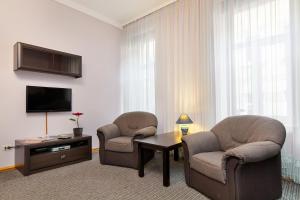 a hotel room with two chairs and a table and a television at Opera Theater Apartments in Lviv