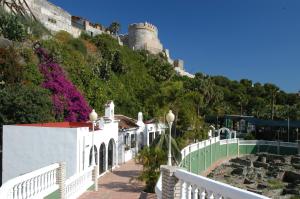 a white building on a hill with a castle in the background at Hotel Victoria Centro in Almuñécar
