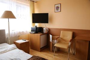 a hotel room with a bed and a chair and a television at Willa Bartek in Ciechocinek