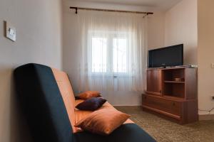 ein Wohnzimmer mit einem Sofa und einem TV in der Unterkunft Apartments Kronja in Grebaštica