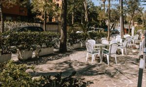 una fila di sedie e tavoli bianchi su un patio di Hotel Garden a Porto San Giorgio