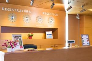 a reception desk with clocks on the wall at De Lita in Druskininkai