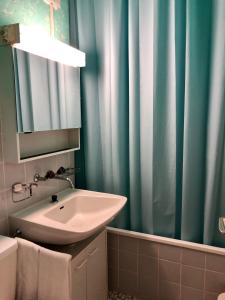 baño con lavabo y cortina de ducha azul en La Prada, en Laax