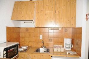 a small kitchen with wooden cabinets and a sink at Studio Les Iris 18 Station Thollon les Mémises in Thollon