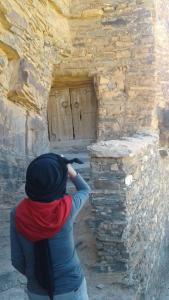 une femme prenant une photo d'une porte dans un mur de pierre dans l'établissement Amtoudi Aventure, à Id AÃ¯ssa