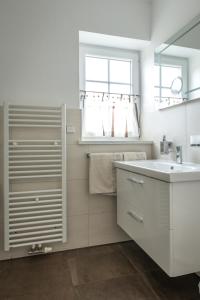ein weißes Badezimmer mit einem Waschbecken und einem Spiegel in der Unterkunft Ferienwohnungen Schön in Teltow