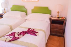 a bedroom with two beds with white sheets and a night stand at Hotel Villa Sirina in Taormina