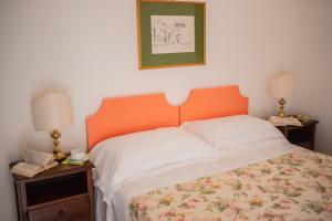 a bedroom with a bed with an orange headboard and two lamps at Hotel Villa Sirina in Taormina