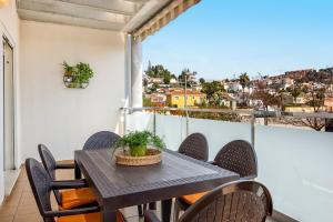 einen Tisch und Stühle auf einem Balkon mit Stadtblick in der Unterkunft WintowinRentals Best Location, Beach, Pool & Parking in Rincón de la Victoria