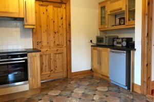 a kitchen with wooden cabinets and a dishwasher at Cottage 173 - Clifden in Clifden