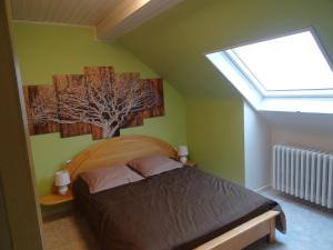 a bedroom with a bed with a tree picture on the wall at Gîte Henry in Orbey