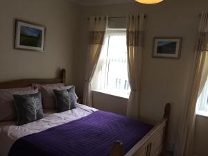 a bedroom with a bed with purple sheets and a window at 94 High Street in Cross Hands