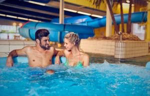 a man and a woman in a swimming pool at WestCord ApartHotel Boschrijck in West-Terschelling