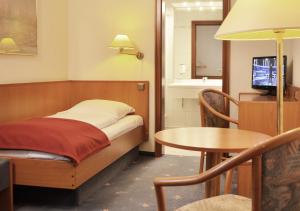 Habitación con cama, mesa y TV. en Hotel Waldhusen - Adults Only, en Kücknitz