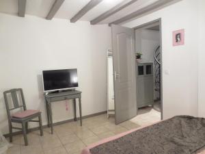 a living room with a television and a table with a chair at Le Grand Coudreau in Nazelles
