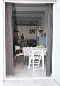 uma sala de jantar com uma mesa branca e cadeiras em Au Coin des Cerisiers em Montclus