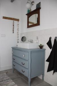 y baño con lavabo azul y espejo. en Au Coin des Cerisiers, en Montclus