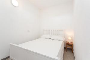 a white bedroom with a white bed and a lamp at Casa Leonardo in Casamicciola Terme