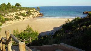 a beach with a wooden fence and the ocean at Duplex Ancla in L'Ametlla de Mar