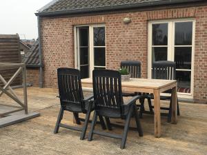 una mesa de madera y 4 sillas en una terraza en Guesthouse De Middelvelden en Arendonk