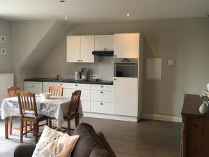 a kitchen with white cabinets and a table and chairs at Guesthouse De Middelvelden in Arendonk