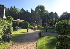 einen Ziegelweg mit einem Regenschirm und einem Tisch im Garten in der Unterkunft Hotel Waldhusen - Adults Only in Kücknitz