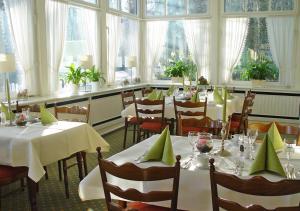 un ristorante con tavoli e sedie bianchi e finestre di Hotel Waldhusen - Adults Only a Kücknitz