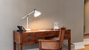 a wooden desk with a lamp and a telephone at Blue City Boutique Hotel in Baden