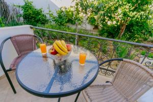 a glass table with a bowl of fruit and two glasses of orange juice at Apartments SoleMar2 in Sutomore
