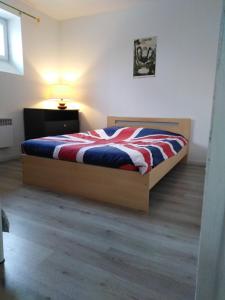 um quarto com uma cama com um cobertor vermelho branco e azul em Gîte du Petit Gué em Frossay