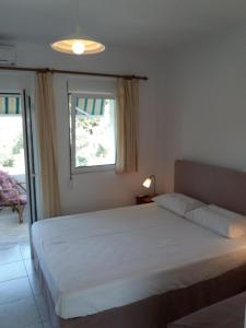 a bedroom with a white bed and a window at Anessis in Sarakiniko